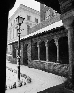 855672 Gezicht in de besneeuwde kruisgang van de Mariakerk te Utrecht, met links een klassieke lantaarnpaal.